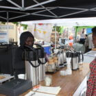 Koliesha Banks serves a customer at the Wildflyer Coffee stand at the Linden Hills Farmers Market. Wildflyer is raising funds to find a permanent location so they can employ more unstably housed youth and provide them with regular hours. Photo by Andrew Hazzard
