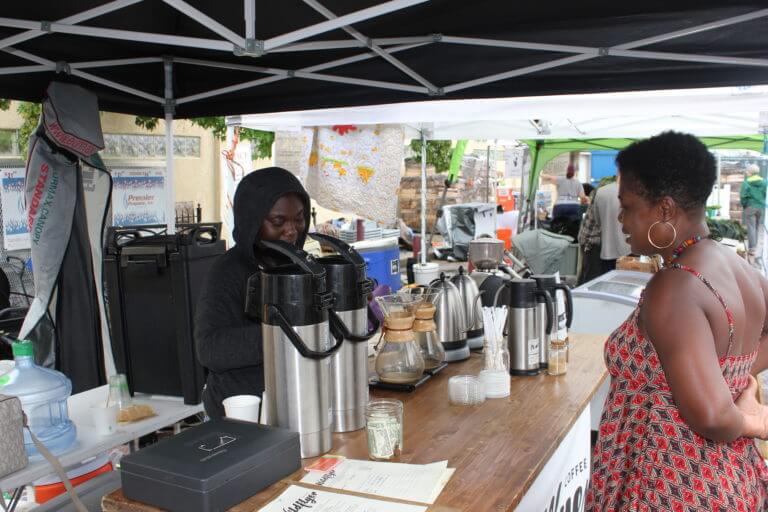 Koliesha Banks serves a customer at the Wildflyer Coffee stand at the Linden Hills Farmers Market. Wildflyer is raising funds to find a permanent location so they can employ more unstably housed youth and provide them with regular hours. Photo by Andrew Hazzard